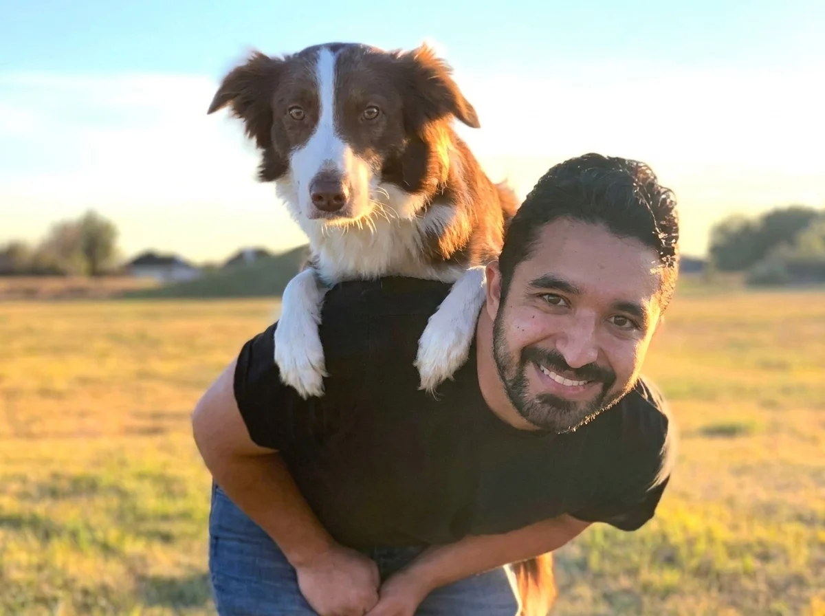 Steven Tallas of Venture Dog Training with a border collie on his shoulders at sunset in Austin, TX